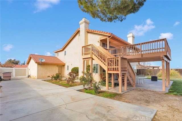 back of house featuring a patio, stairway, a chimney, and fence