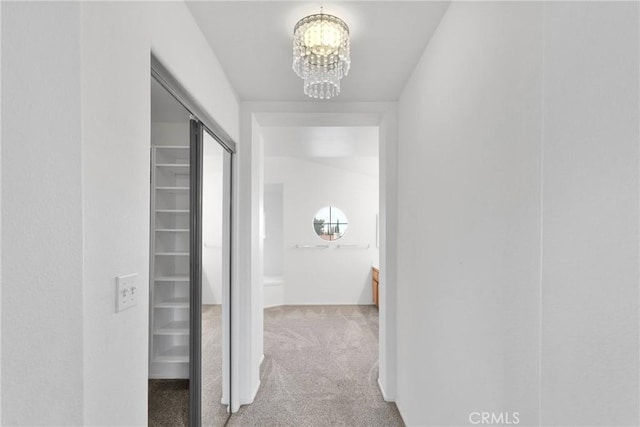 corridor featuring a notable chandelier and carpet flooring