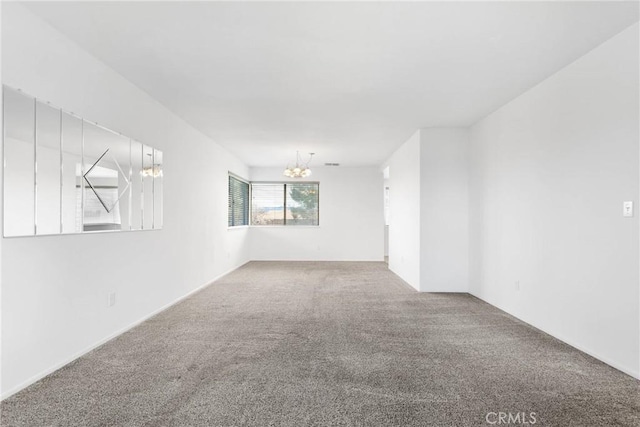 empty room featuring carpet floors and a chandelier