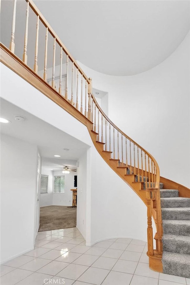 staircase featuring tile patterned flooring and a high ceiling