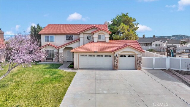 mediterranean / spanish-style house featuring a tile roof, fence, a gate, a front lawn, and a chimney