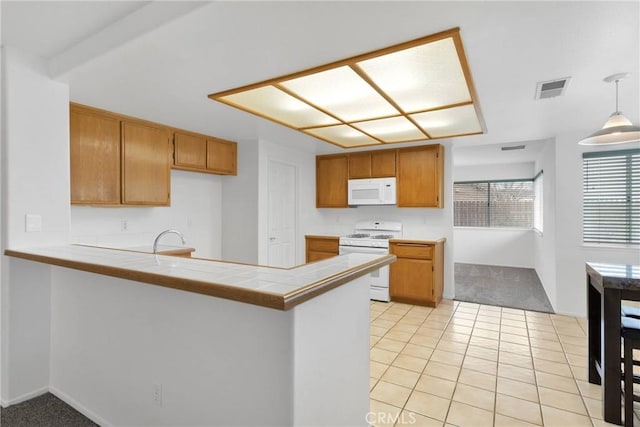 kitchen with a peninsula, white appliances, brown cabinetry, and visible vents