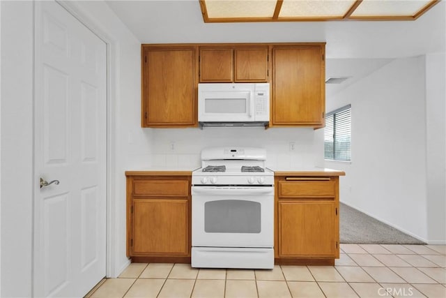 kitchen featuring light tile patterned floors, light countertops, brown cabinetry, white appliances, and baseboards