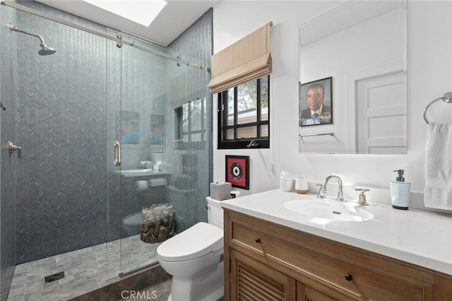 full bathroom with vanity, toilet, a skylight, and a shower stall