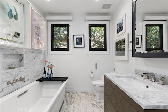 bathroom with vanity, baseboards, a soaking tub, toilet, and marble finish floor