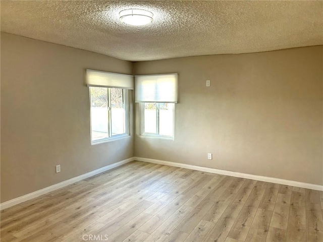 unfurnished room featuring light wood-type flooring, a textured ceiling, and baseboards