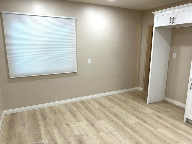 spare room featuring baseboards and light wood-style floors