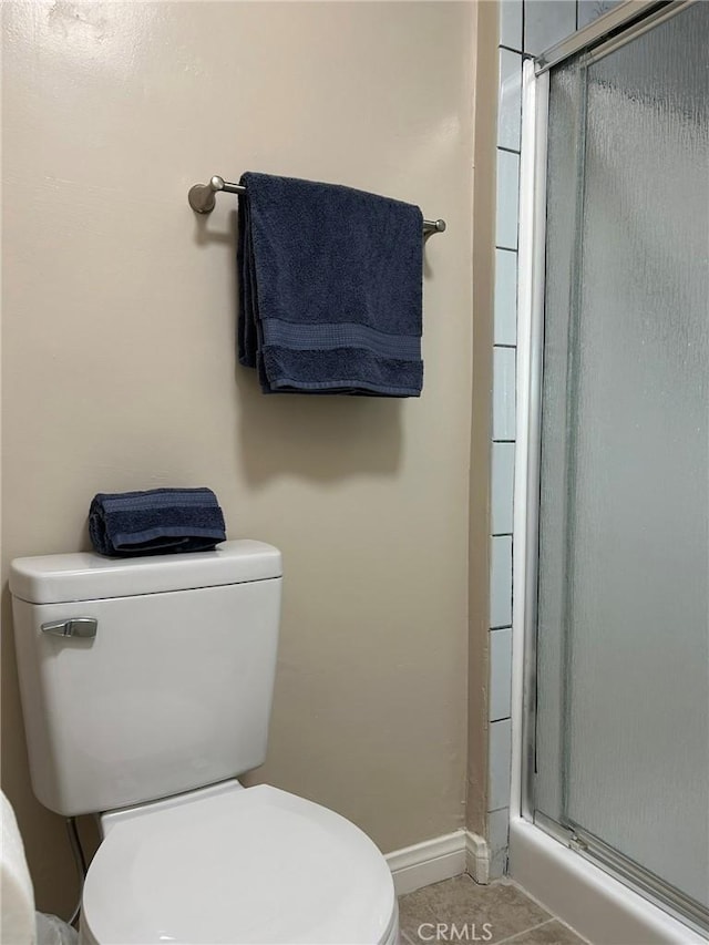 bathroom with baseboards, a shower stall, toilet, and tile patterned floors