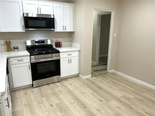 kitchen with white cabinets, light wood finished floors, stainless steel appliances, and light countertops