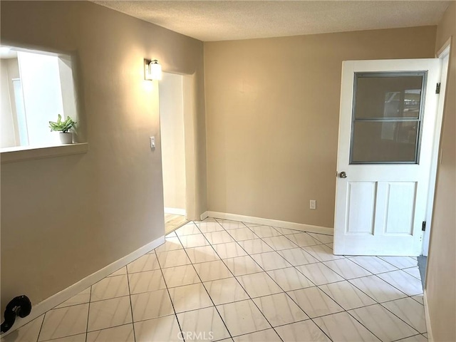 unfurnished room featuring light tile patterned floors, baseboards, and a textured ceiling