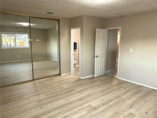 unfurnished bedroom featuring a closet, visible vents, light wood-style flooring, and baseboards