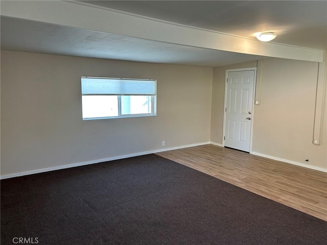 carpeted empty room with baseboards and wood finished floors