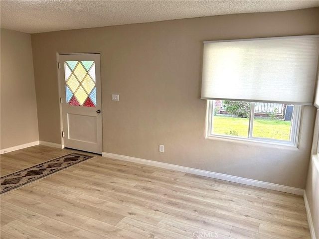 entryway featuring baseboards, a textured ceiling, and light wood-style floors