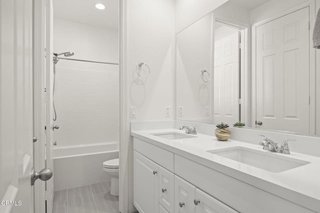 bathroom featuring toilet, double vanity, bathtub / shower combination, and a sink