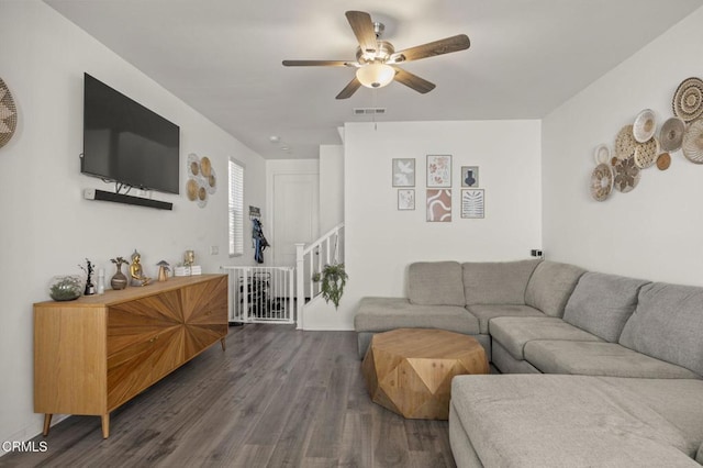 living area with ceiling fan, wood finished floors, and stairs