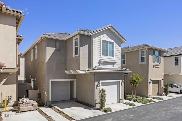 view of front of home featuring an attached garage, a tile roof, a residential view, and stucco siding