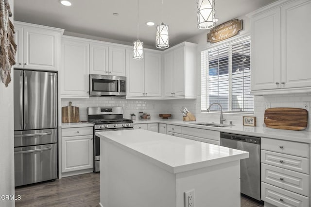 kitchen with stainless steel appliances, a center island, white cabinetry, and a sink