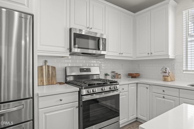 kitchen featuring light countertops, white cabinetry, wood finished floors, stainless steel appliances, and decorative backsplash