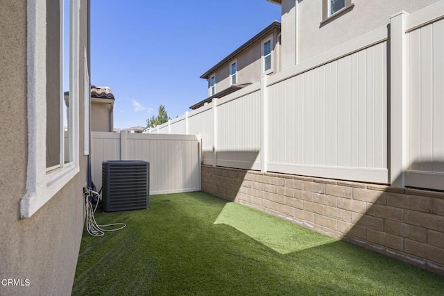view of yard featuring central AC and fence