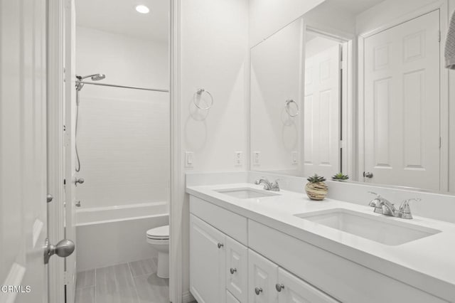 bathroom featuring toilet, bathing tub / shower combination, double vanity, and a sink