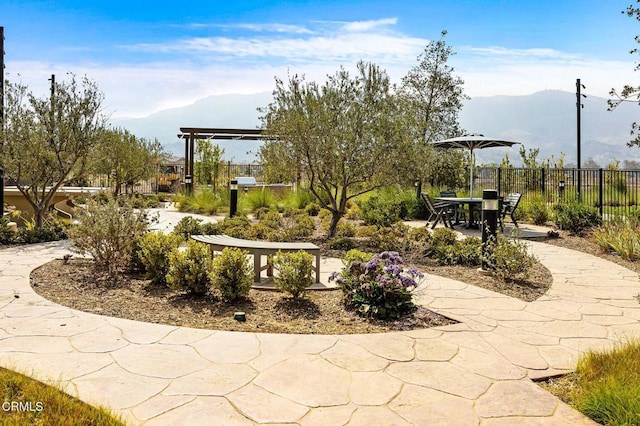 view of home's community with fence, a patio area, and a mountain view