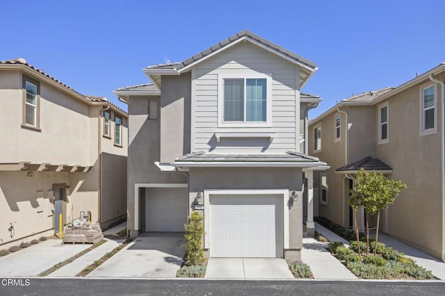 traditional-style home with a garage, driveway, a tiled roof, and stucco siding