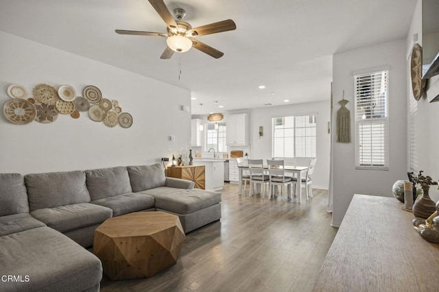 living room with light wood-style flooring, a ceiling fan, and recessed lighting