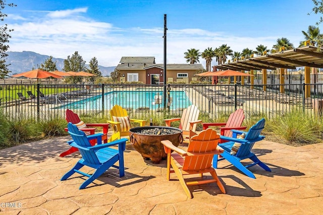 view of patio / terrace featuring an outdoor fire pit, a mountain view, a community pool, and fence
