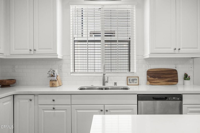 kitchen featuring tasteful backsplash, white cabinetry, dishwasher, light countertops, and a sink