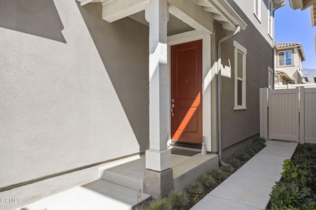 property entrance featuring stucco siding and fence