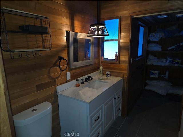 bathroom featuring tile patterned floors, toilet, wood walls, and vanity