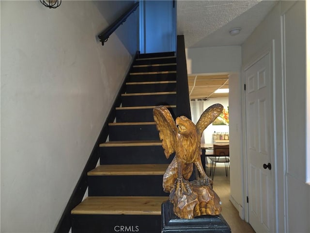 stairs featuring a textured ceiling