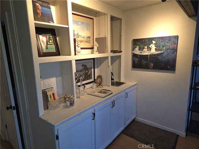 bar featuring baseboards and a sink