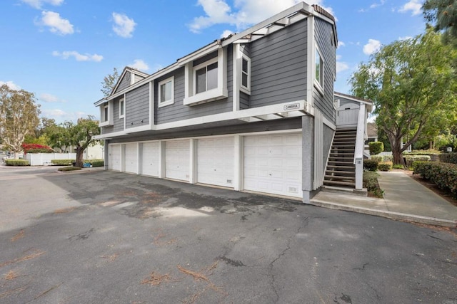 view of home's exterior with community garages and stairway