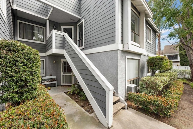 doorway to property featuring fence and stucco siding