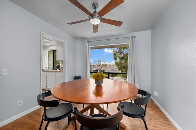 dining room with a wealth of natural light, light wood-type flooring, baseboards, and ceiling fan