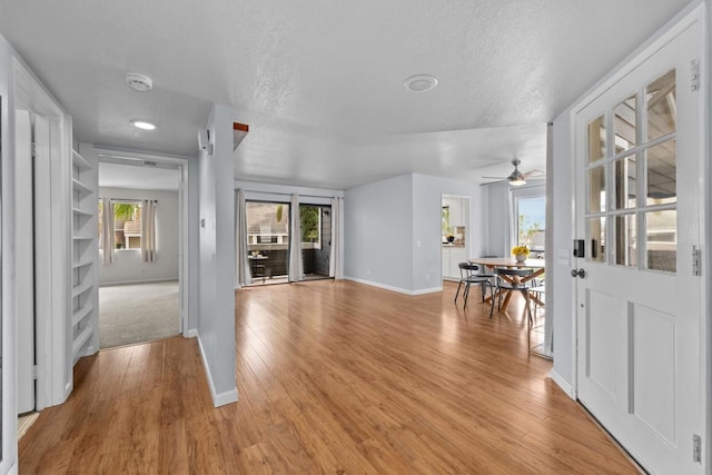 foyer entrance featuring baseboards, a textured ceiling, and light wood-style flooring