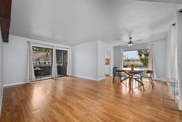 unfurnished dining area featuring light wood finished floors, a textured ceiling, a ceiling fan, and baseboards