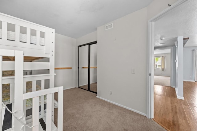 unfurnished bedroom with visible vents, baseboards, a closet, and wood finished floors