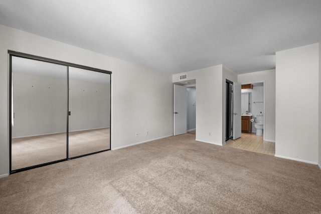 unfurnished bedroom featuring light carpet, visible vents, ensuite bath, and baseboards