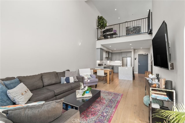 living room featuring recessed lighting, light wood-style flooring, and a towering ceiling