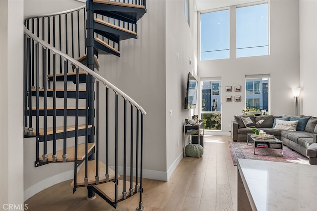 staircase with baseboards, a high ceiling, and wood finished floors