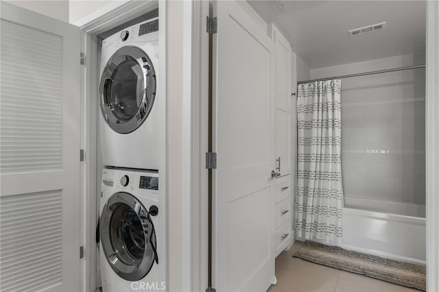 clothes washing area with laundry area, visible vents, and stacked washer / drying machine