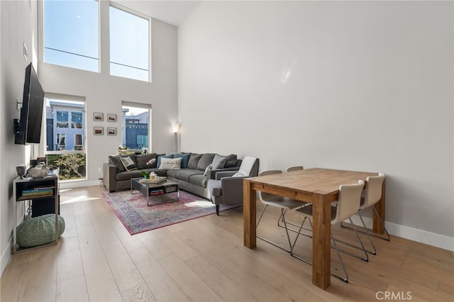 living room featuring light wood-type flooring, a high ceiling, and baseboards