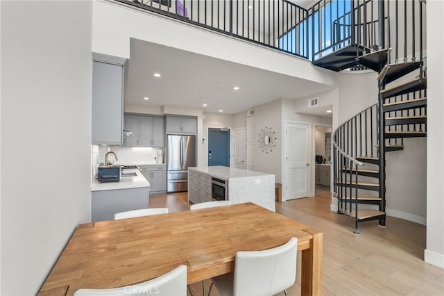 dining room with recessed lighting, stairway, a high ceiling, light wood-style floors, and baseboards