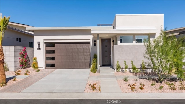 contemporary house featuring concrete driveway, an attached garage, and stucco siding