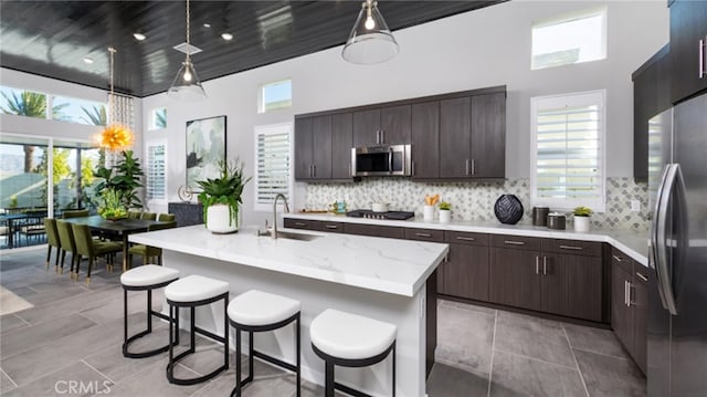 kitchen featuring stainless steel appliances, a sink, dark brown cabinets, and tasteful backsplash