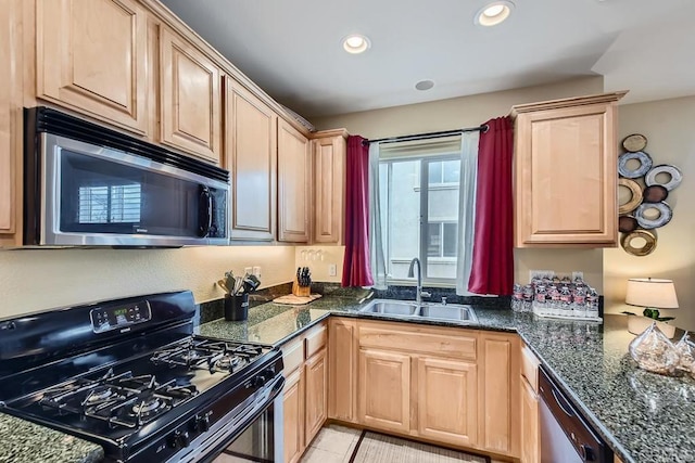 kitchen featuring recessed lighting, stainless steel appliances, a sink, light brown cabinetry, and dark stone countertops