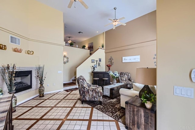 living area featuring light tile patterned floors, baseboards, visible vents, a glass covered fireplace, and ceiling fan