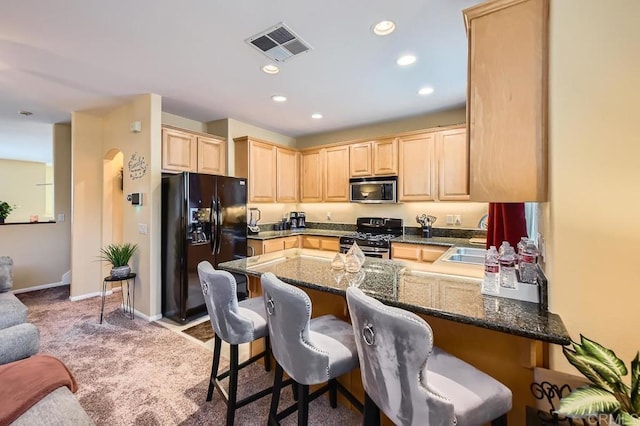 kitchen featuring visible vents, appliances with stainless steel finishes, dark stone countertops, a peninsula, and light brown cabinets